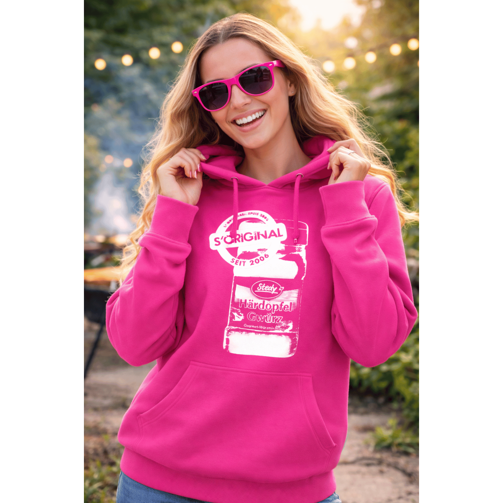 Frau trägt pinken Steady-Hoodie und Sonnenbrille im Outdoor-Setting