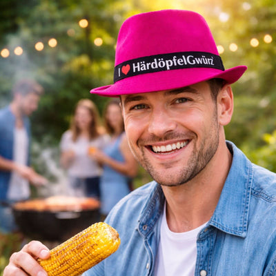 Person trägt pinken Stedy Hut beim Grillen im Freien – gute Stimmung und Genuss