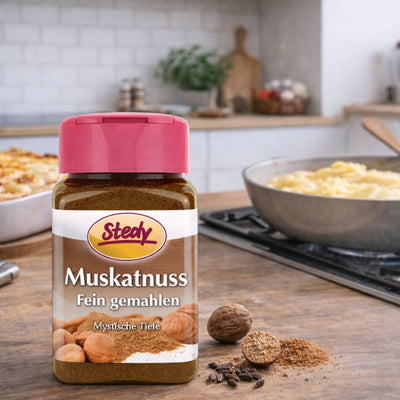 Muskatnuss gemahlen im Streuer in Küchenszene mit ganzen Nüssen im Hintergrund