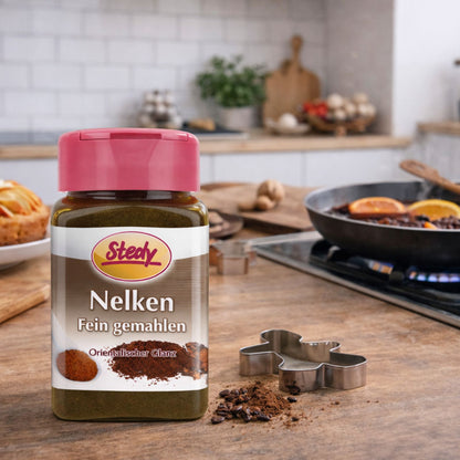 Nelkenpulver im Streuer in der Küche, neben Pfanne und Gewürzen angerichtet
