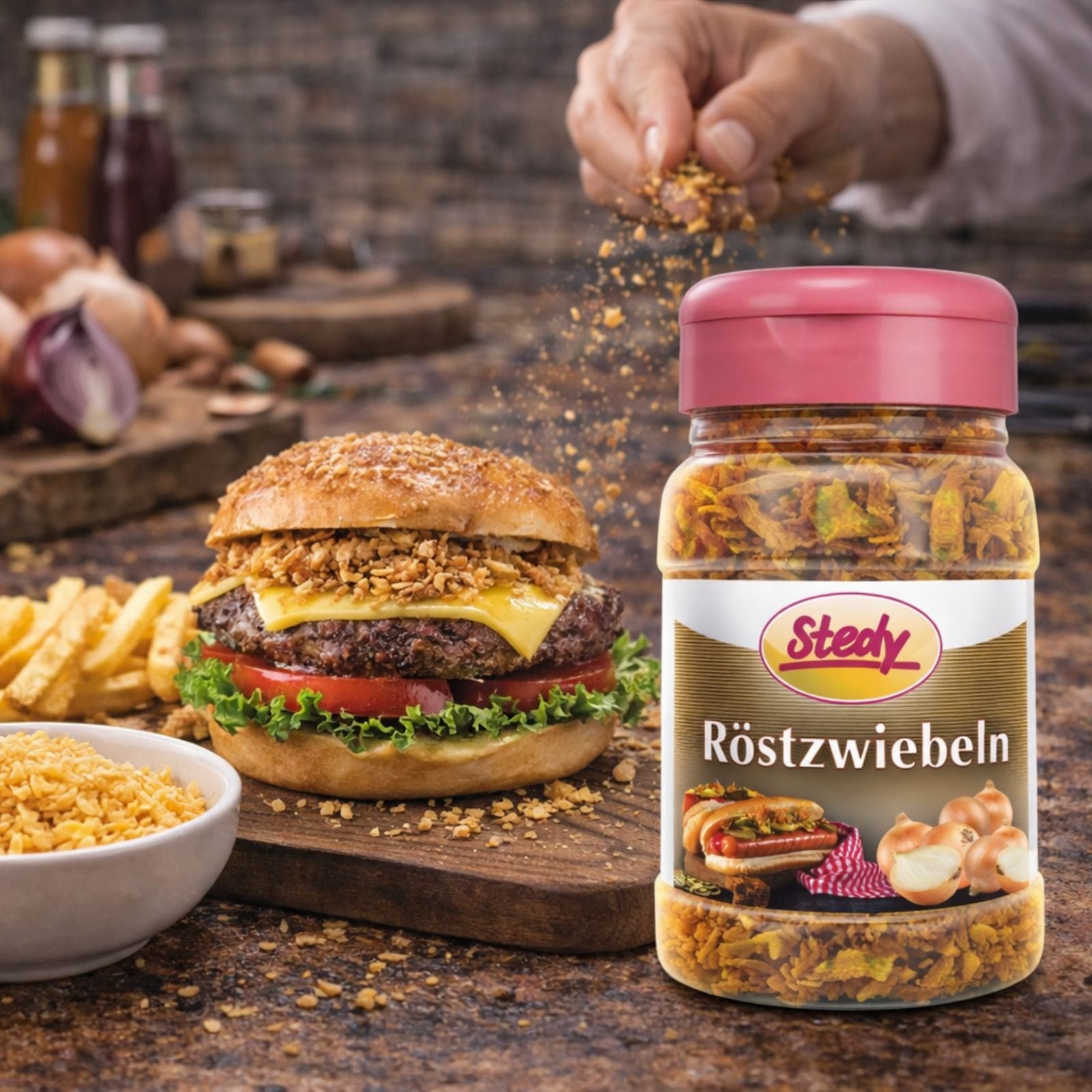 Stedy Röstzwiebeln werden auf Burger gestreut, daneben Pommes und Glas