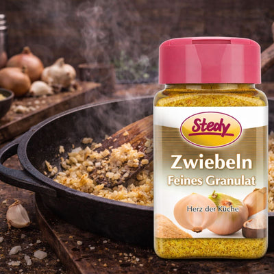 Zwiebelgranulat im Streuer beim Kochen in der Pfanne, rustikale Küchenszene