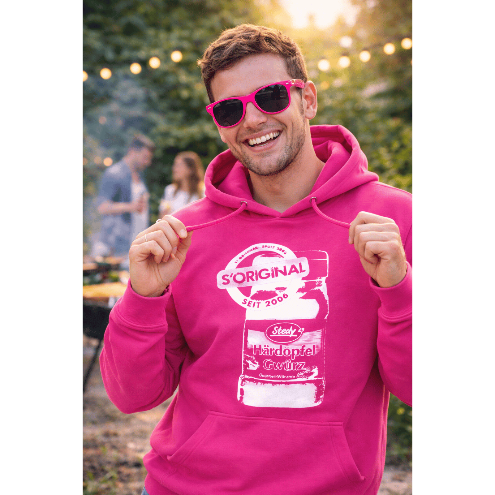 Mann im pinken Steady-Hoodie und Sonnenbrille, lächelnd im Freien